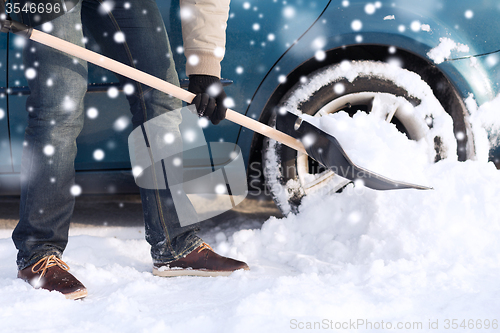 Image of closeup of man digging snow with shovel near car