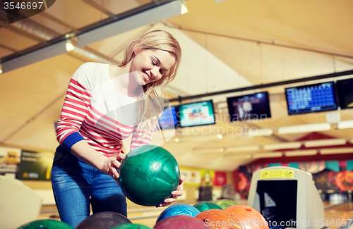 Image of happy young woman holding ball in bowling club