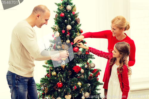 Image of smiling family decorating christmas tree at home