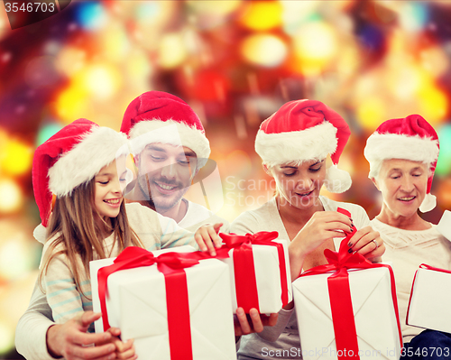 Image of happy family in santa helper hats with gift boxes