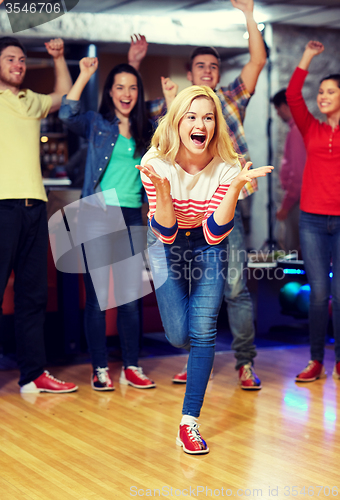 Image of happy young woman throwing ball in bowling club