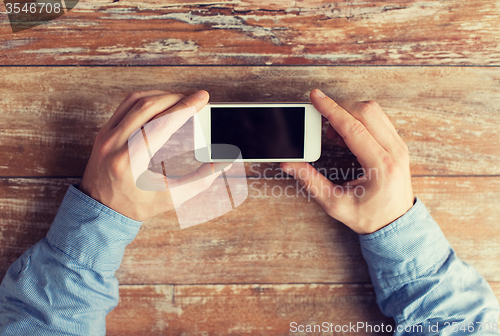 Image of close up of male hands with smartphone on table