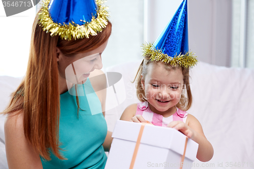 Image of happy mother and child in party caps with gift box