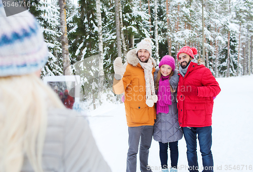 Image of smiling friends with tablet pc in winter forest