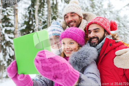 Image of smiling friends with tablet pc in winter forest