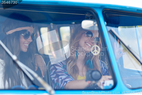 Image of smiling young hippie women driving minivan car