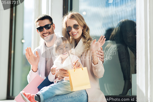 Image of happy family with child and shopping bags in city