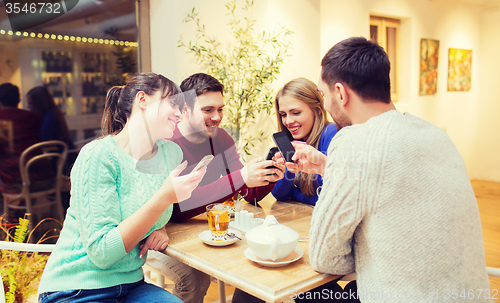 Image of group of friends with smartphones meeting at cafe