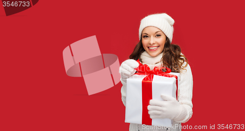 Image of smiling woman in white clothes with gift box