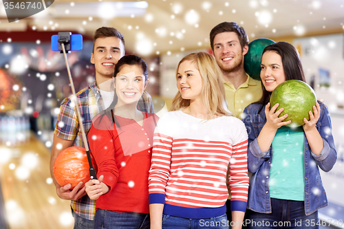 Image of happy friends taking selfie in bowling club