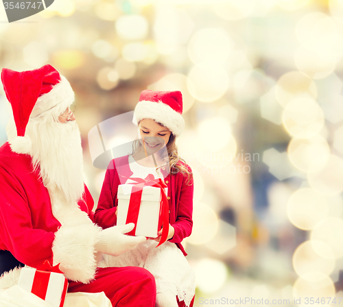 Image of smiling little girl with santa claus and gifts