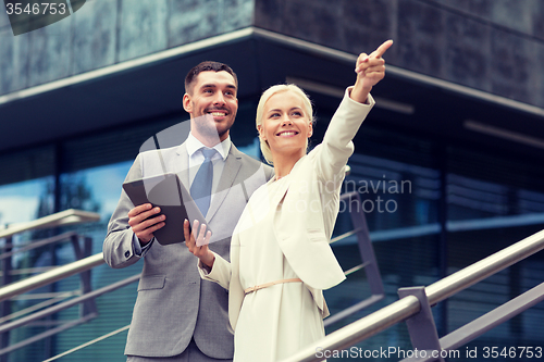 Image of smiling businessmen with tablet pc outdoors