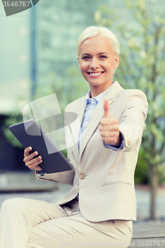 Image of smiling businesswoman with tablet pc outdoors