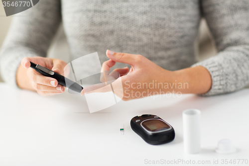 Image of close up of woman making blood test by glucometer