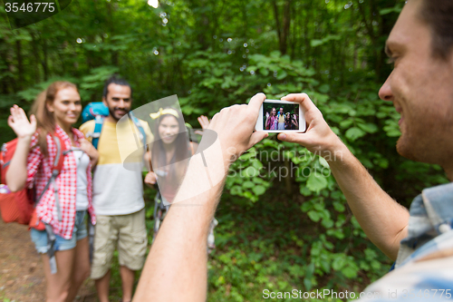 Image of happy man photographing friends by smartphone