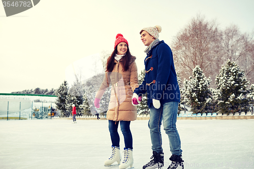 Image of happy couple ice skating on rink outdoors