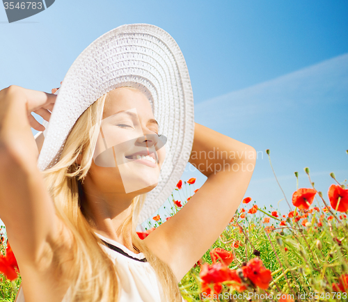 Image of smiling young woman in straw hat on poppy field