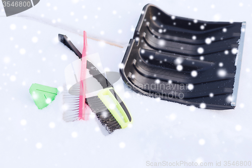 Image of black snowshowel with wooden handle in snow pile