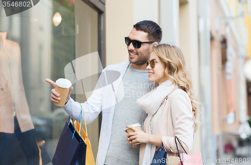 Image of happy couple with shopping bags and coffee in city