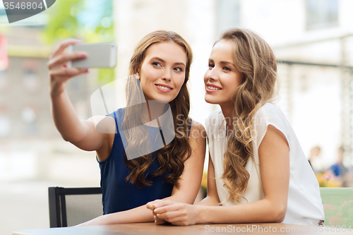Image of happy women with smartphone taking selfie at cafe