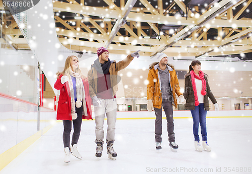 Image of happy friends pointing finger on skating rink