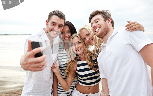 Image of happy friends on beach and taking selfie