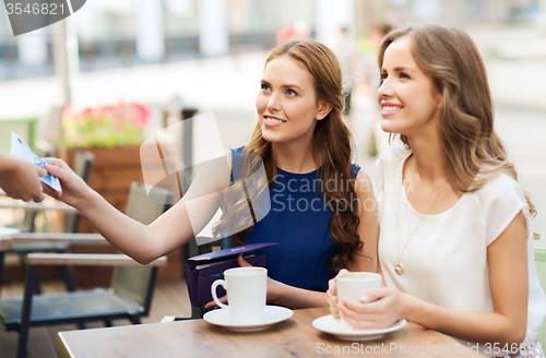 Image of women paying money to waiter for coffee at cafe