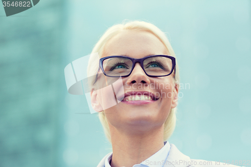 Image of young smiling businesswoman over office building