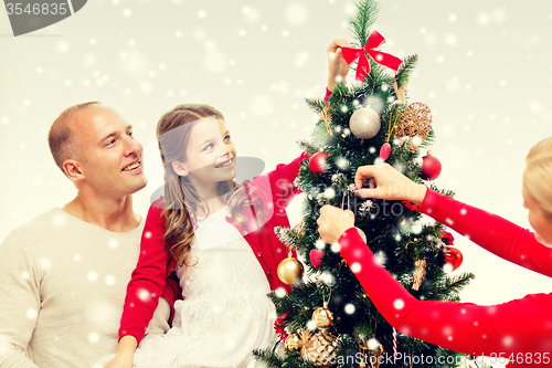 Image of smiling family decorating christmas tree at home