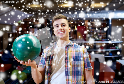 Image of happy young man holding ball in bowling club