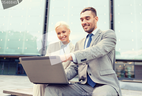 Image of smiling businesspeople with laptop outdoors