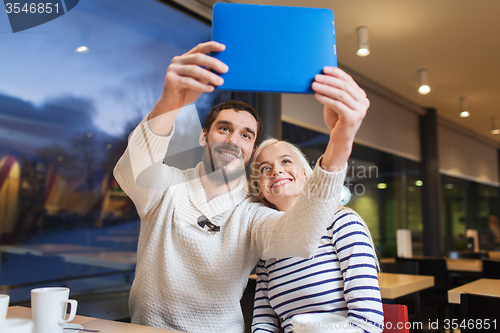 Image of happy couple with tablet pc taking selfie at cafe