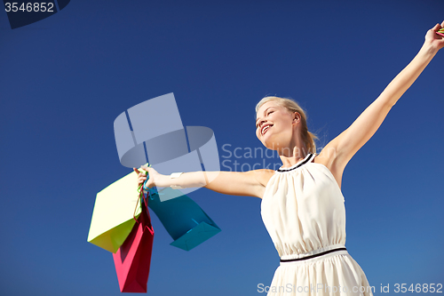 Image of smiling woman with shopping bag rising hands