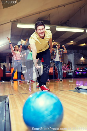 Image of happy young man throwing ball in bowling club