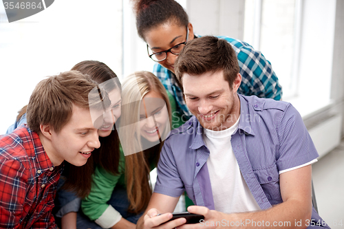 Image of group of happy students with smartphone at school