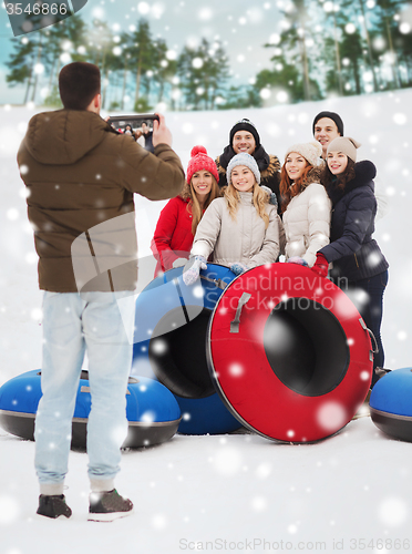 Image of group of smiling friends with snow tubes