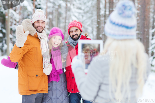 Image of smiling friends with tablet pc in winter forest