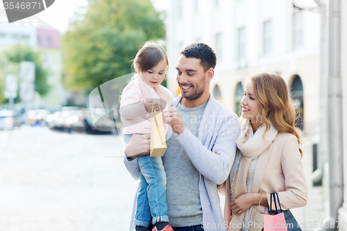 Image of happy family with child and shopping bags in city