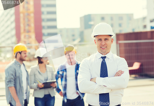 Image of group of smiling builders in hardhats outdoors