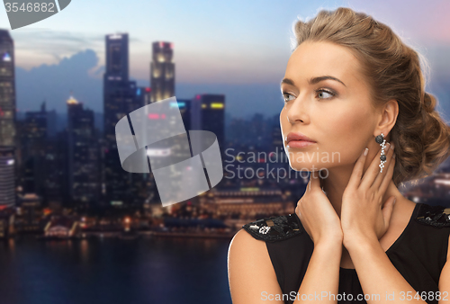 Image of beautiful woman wearing earrings over evening city