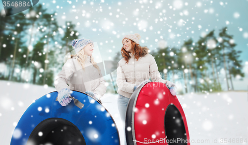 Image of happy girl friends with snow tubes outdoors
