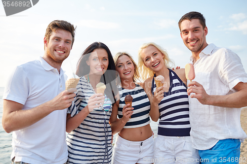 Image of smiling friends eating ice cream on beach