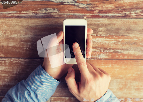 Image of close up of male hands with smartphone on table