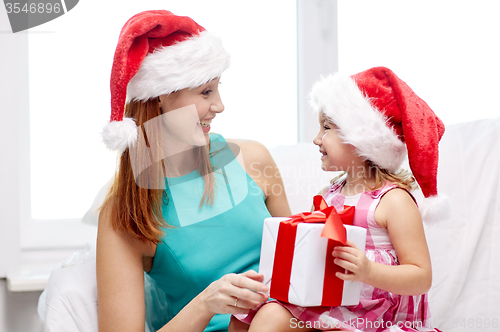 Image of happy mother and child in santa hats with gift box