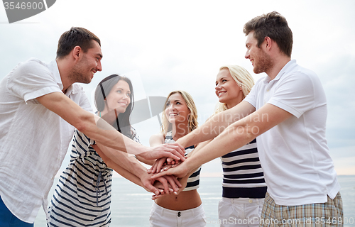 Image of smiling friends putting hands on top of each other