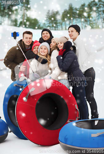 Image of group of smiling friends with snow tubes