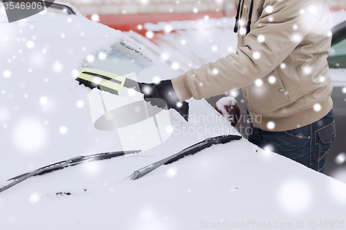 Image of closeup of man cleaning snow from car