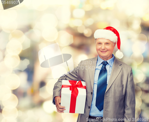 Image of smiling man in suit and santa helper hat with gift