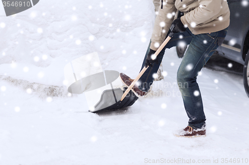 Image of closeup of man digging snow with shovel near car