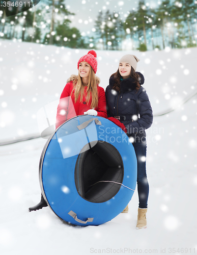 Image of happy girl friends with snow tubes outdoors